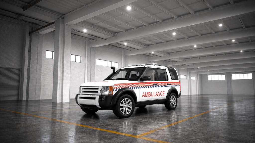 A white and red ambulance parked in a spacious, well-lit garage or warehouse.