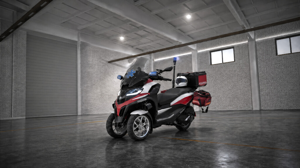 A red and white delivery scooter parked in a spacious warehouse setting.