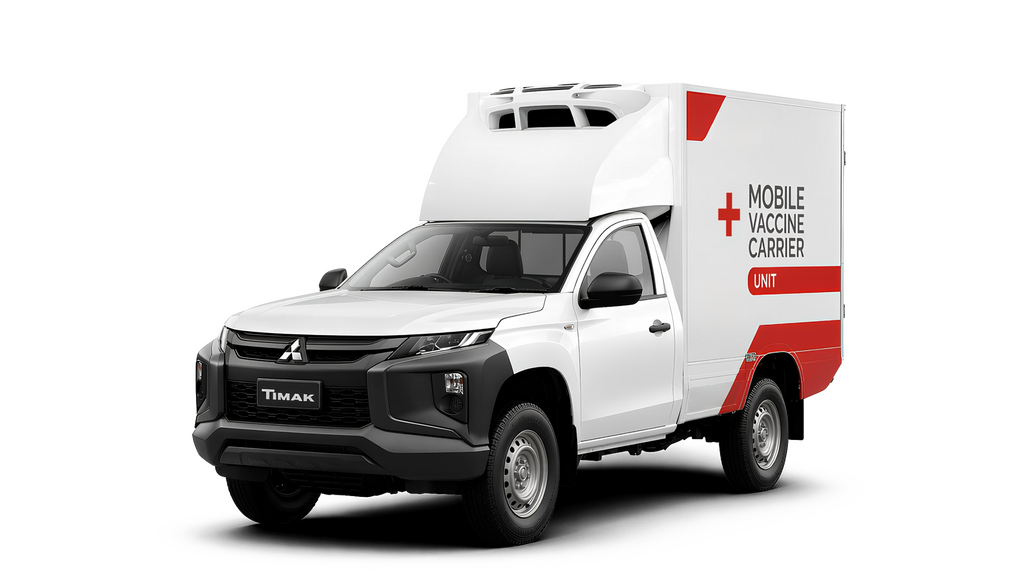 A white Mitsubishi pickup truck with a mobile vaccine carrier unit attached to the bed, featuring red accents and a distinctive roof rack, set against a solid black background.